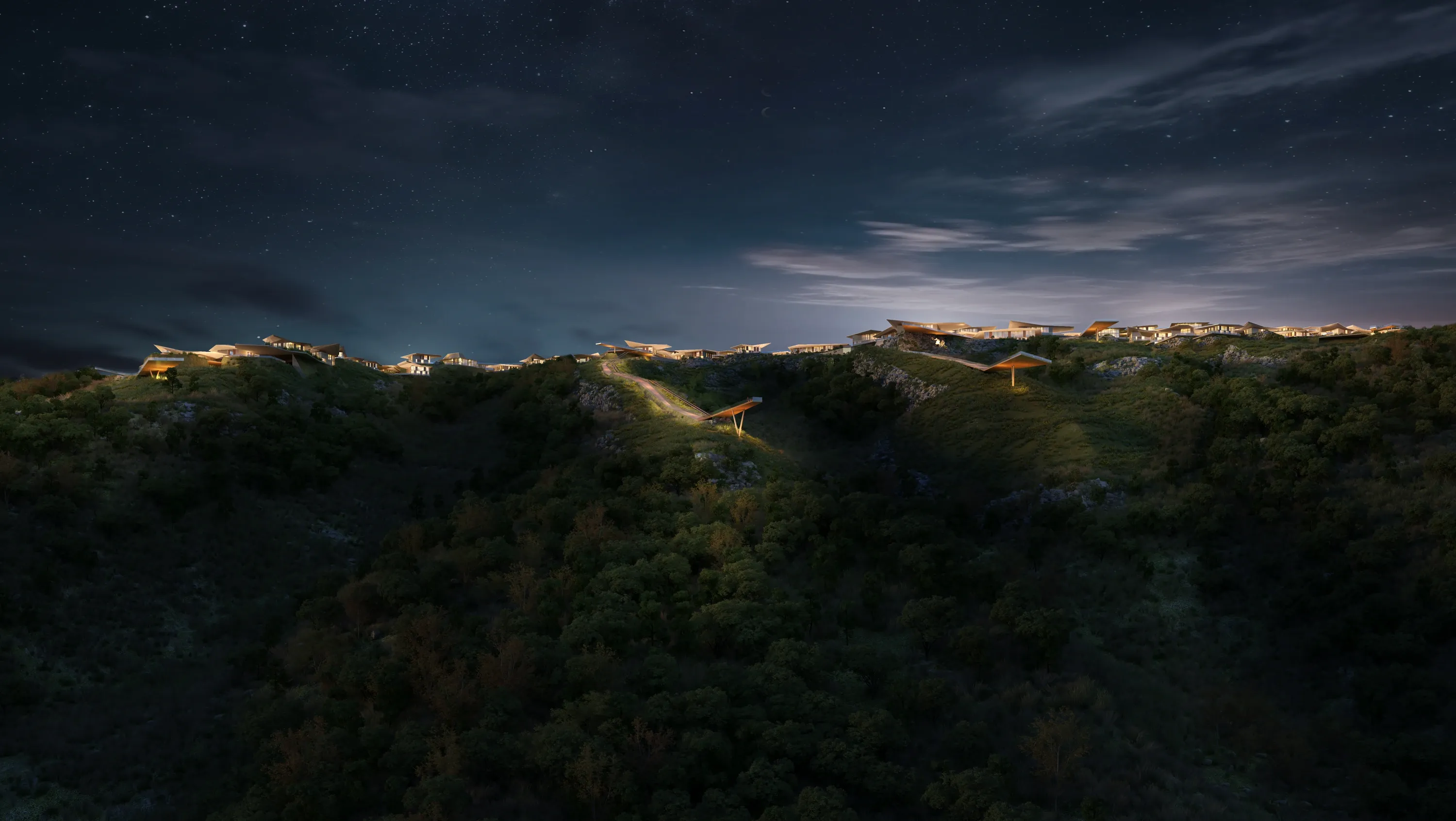 Mira Verde lit along the hillside at night, seen across the wooded slopes